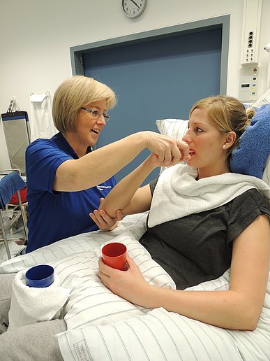 eine Patientin wird unterstützt bei einer Tätigkeit des täglichen Lebens, hier die Mundpflege